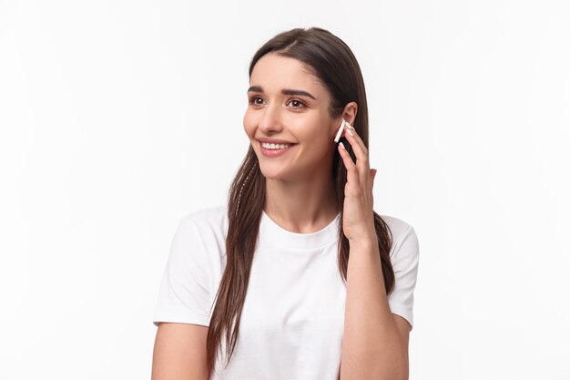 Retrato de primer plano de la atractiva mujer morena joven sonriente hablando por teléfono