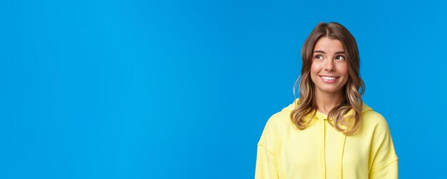 Retrato de primer plano de una atractiva mujer rubia europea con el pelo corto y una sudadera con capucha amarilla que parece drea