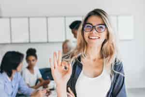 Foto gratuita retrato de primer plano de bastante mujer gerente del departamento de ventas. foto interior de mujer sonriente que trabaja en la oficina con discutir personas.