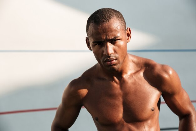 Retrato de primer plano de cansado serio guapo afroamericano deportista, descansando después de hacer ejercicio en el estadio