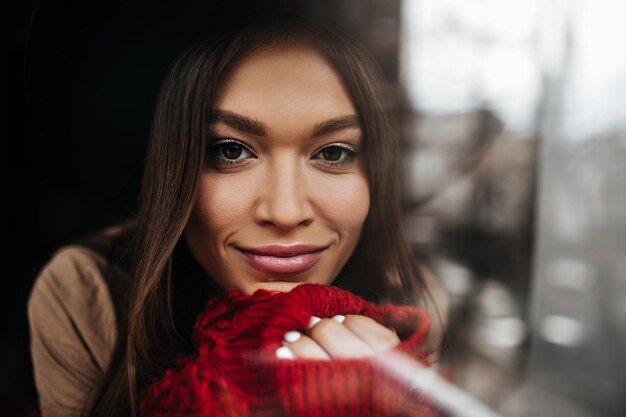 Retrato de primer plano de una chica de ojos marrones oscuros con cabello lacio lindo sonriendo y mirando a la cámara