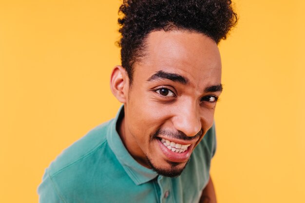 Retrato de primer plano de chico alegre de moda con ojos marrones. Modelo masculino africano en traje verde que expresa emociones sinceras.