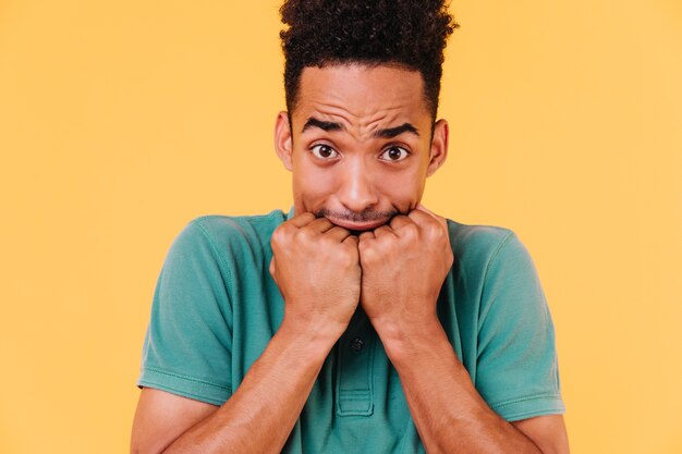 Retrato de primer plano de chico preocupado con elegante corte de pelo. Foto de hombre negro asustado aislado.