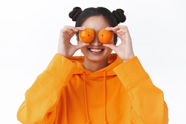 Retrato de primer plano de despreocupado lindo y tonto adolescente asiático haciendo ojos de mandarinas y sonriendo, divirtiéndose