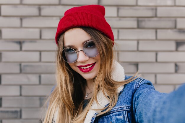 Retrato de primer plano de encantadora mujer sensual con labios rojos. Chica caucásica refinada pasar la mañana de primavera al aire libre.