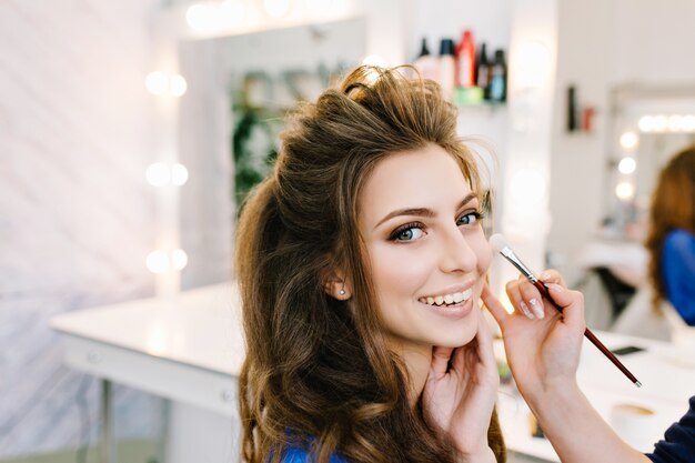 Retrato de primer plano con estilo de hermosa mujer joven con hermoso peinado sonriendo en salón de peluquería