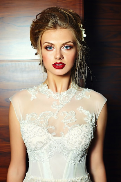 Retrato de primer plano de glamour de hermosa novia rubia con maquillaje brillante y labios rojos