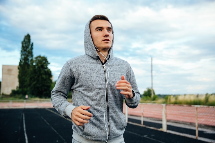 Foto gratuito retrato de primer plano de un guapo deportista corriendo, vistiendo sudadera con capucha