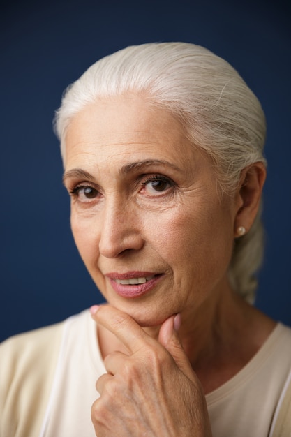 Foto gratuita retrato de primer plano de hermosa anciana con cabello plateado, sosteniendo su barbilla