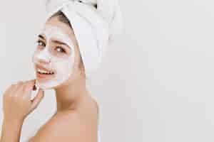 Foto gratuita retrato de primer plano de hermosa mujer joven con toallas después de tomar el baño hacer mascarilla cosmética en su rostro.