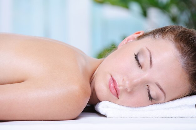 Retrato de primer plano de hermosa niña relajante en el salón de spa