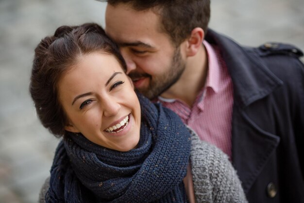 Retrato de primer plano de hombre besando a su novia en la calle. Hombre barbudo enamorado de su mujer.