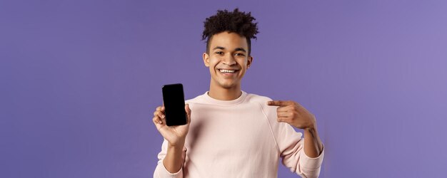 Retrato de primer plano de un hombre joven y guapo que promueve la aplicación para teléfonos inteligentes o la entrega de compras en línea por Internet