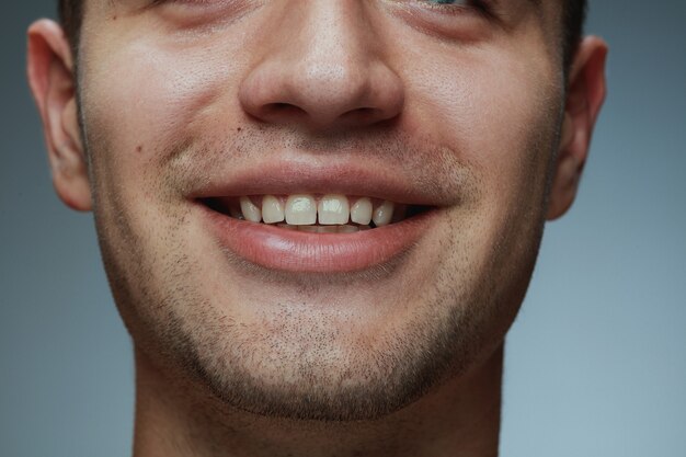 Retrato de primer plano de joven aislado sobre fondo gris. La cara y los labios del modelo masculino caucásico.