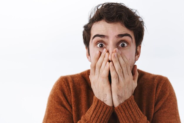 Foto gratuita retrato de primer plano de un joven apuesto sorprendido sorprendido con cerdas mirando asombrado con los ojos reventados jadeando tapando la boca con las manos como si estuviera muy impresionado fondo blanco