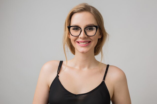 Retrato de primer plano de joven atractiva mujer sexy con gafas elegantes, inteligente y segura, sonriente y feliz, vestido negro, estilo elegante, modelo posando sobre fondo blanco de estudio, aislado