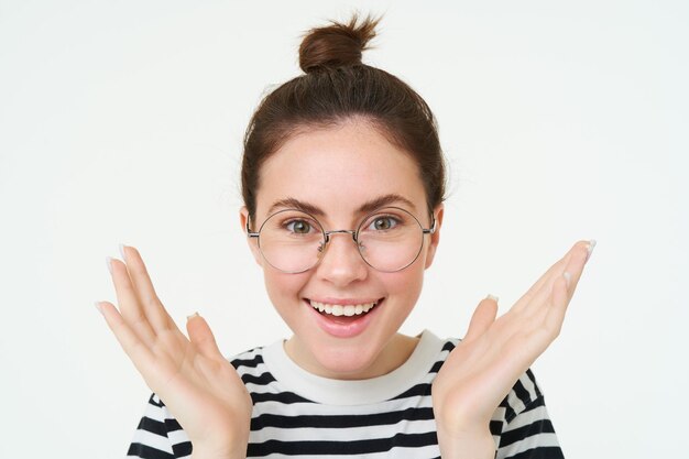 Foto gratuita retrato en primer plano de una joven feliz y asombrada con gafas, manos apretadas, aplausos, aplauso y sonrisa.