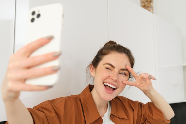 Foto gratuita retrato en primer plano de una joven feliz y positiva que se toma una selfie con un teléfono móvil posando para una foto en