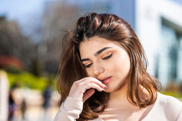 Retrato de primer plano de una joven hermosa que se lleva la mano a la boca y mira hacia abajo Foto de alta calidad