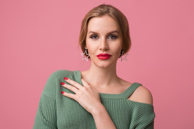 Retrato de primer plano de joven mujer atractiva sexy, maquillaje elegante, labios rojos, suéter verde, modelo posando en estudio, fondo rosa aislado, pendientes, mirando a puerta cerrada