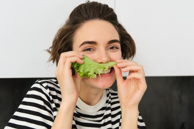 Retrato en primer plano de una joven vegetariana a la que le gusta comer verduras posando con hojas de lechuga