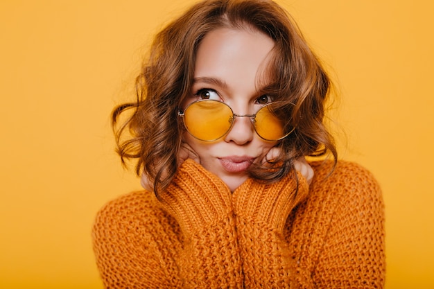 Foto gratuita retrato de primer plano de linda mujer pensativa con rizos brillantes mirando a otro lado sobre fondo amarillo