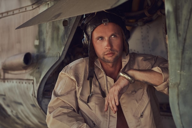 Foto gratuita retrato de primer plano de un mecánico en uniforme y volando cerca, parado debajo de un viejo avión bombardero en el museo al aire libre.