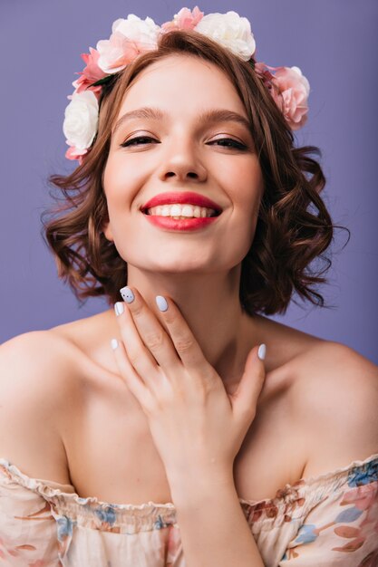 Retrato de primer plano de mujer alegre con maquillaje y manicura de moda. sonriente niña adorable en corona de flores.