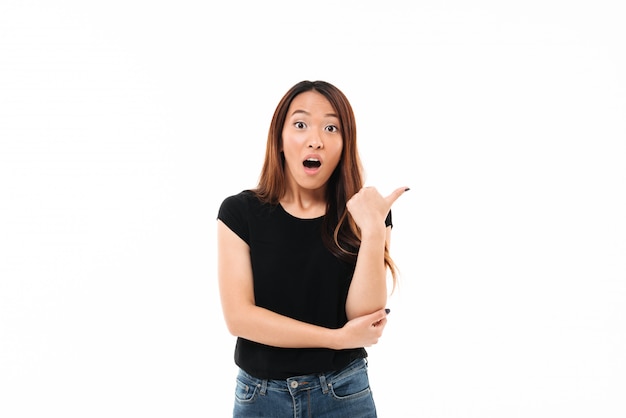 Retrato de primer plano de mujer bastante asiática joven sorprendida mostrando pulgar arriba gesto, mirando a la cámara