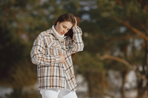 Retrato de primer plano de mujer con chaqueta negra. Mujer de pie en un bosque en día de nieve.