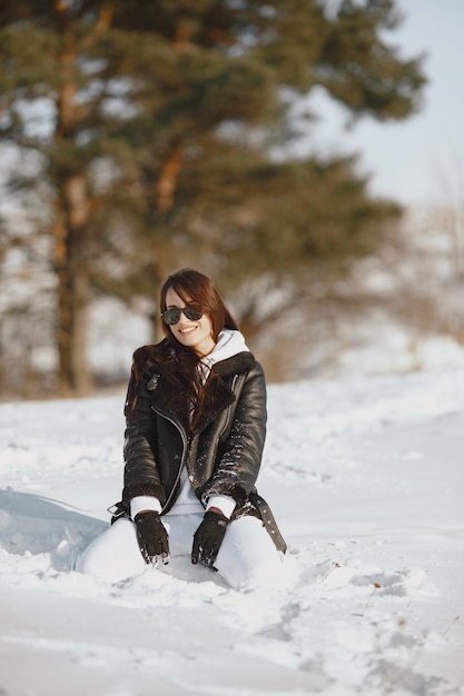 Retrato de primer plano de mujer con chaqueta negra. Mujer de pie en un bosque en día de nieve.