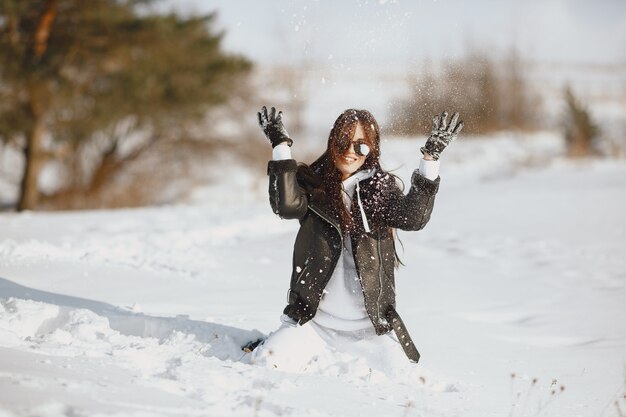 Retrato de primer plano de mujer con chaqueta negra. Mujer de pie en un bosque en día de nieve.