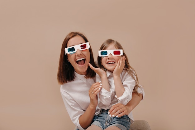 Retrato de primer plano de mujer feliz con niña viendo una película en gafas 3D con emociones sorprendidas