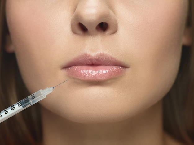 Foto gratuita retrato de primer plano de una mujer joven en la pared blanca. procedimiento de cirugía de llenado. aumento de labios. concepto de salud y belleza de la mujer, cosmetología, autocuidado, cuidado corporal y de la piel. anti-envejecimiento.