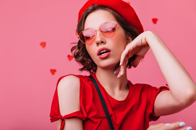 Retrato de primer plano de mujer sensual pensativa en boina roja. Chica seria de moda con corte de pelo corto posando.