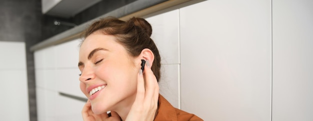 Retrato en primer plano de una mujer sonriendo de la calidad del sonido en sus auriculares negros inalámbricos escuchando