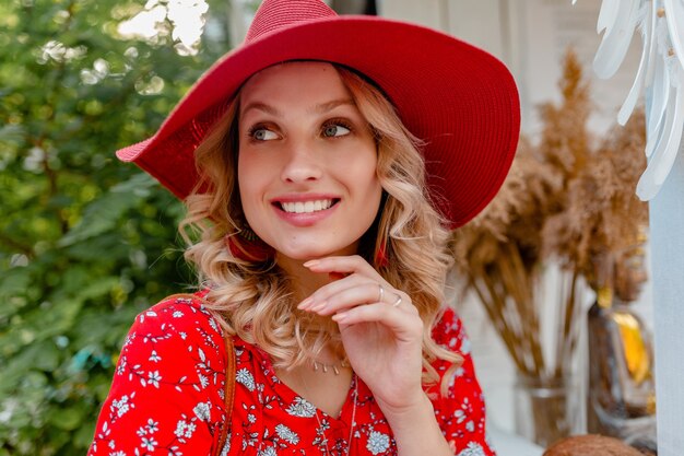 Retrato de primer plano de mujer sonriente rubia con estilo atractivo en traje de moda de verano de blusa y sombrero rojo de paja con sonrisa