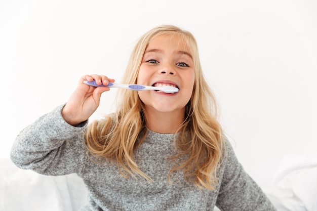 Retrato de primer plano de niño lindo en pijama gris cepillarse los dientes