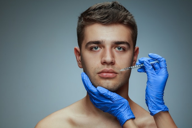 Retrato de primer plano de perfil de joven aislado en estudio gris, procedimiento de cirugía de llenado