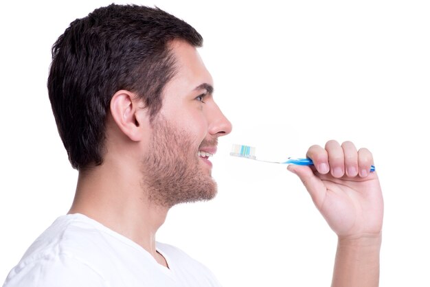 Retrato de primer plano de perfil de un joven feliz con un cepillo de dientes - aislado en blanco.