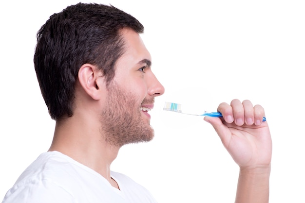 Retrato de primer plano de perfil de un joven feliz con un cepillo de dientes - aislado en blanco.