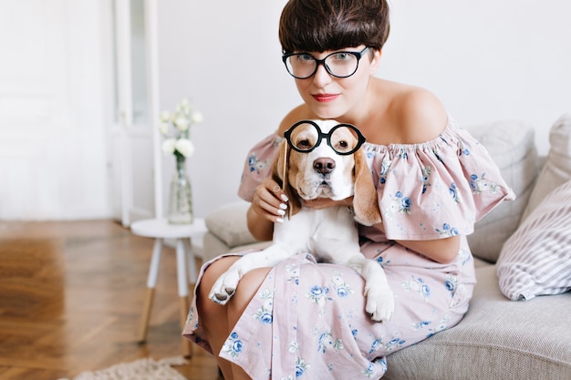 Retrato de primer plano de perro beagle con grandes ojos tristes y chica alegre con corte de pelo corto con gafas