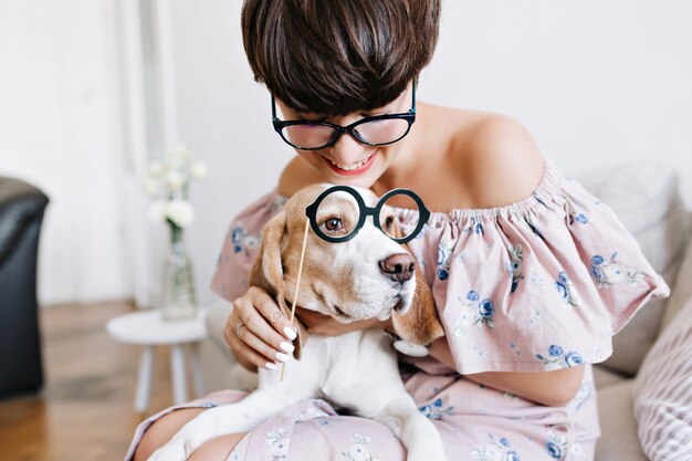 Retrato de primer plano de perro beagle con grandes ojos tristes y chica alegre con corte de pelo corto con gafas