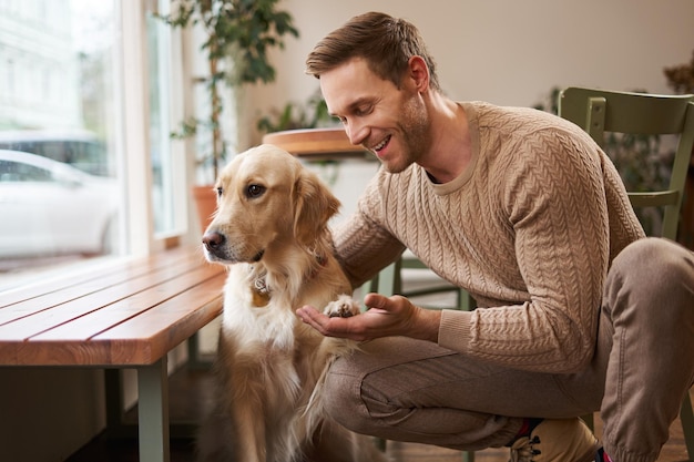 Retrato en primer plano de un perro lindo y inteligente que le da la pata a su dueño un hombre guapo con su golden retriever