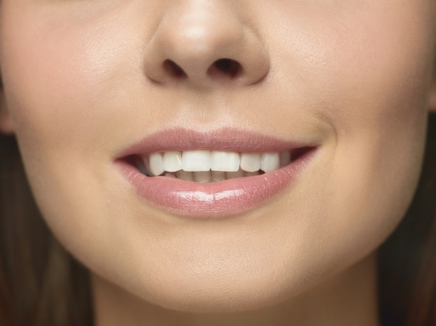 Retrato de primer plano del rostro de mujer joven. Modelo de mujer con piel cuidada y labios grandes sonriendo.