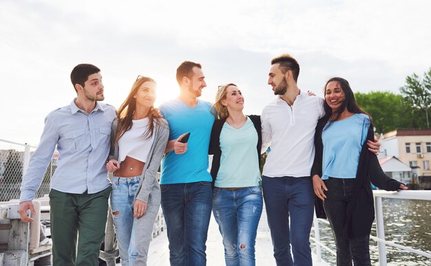 Retrato de un pueblo joven y feliz en reposo en el muelle. Amigos disfrutando de un juego en el lago. Emociones positivas.