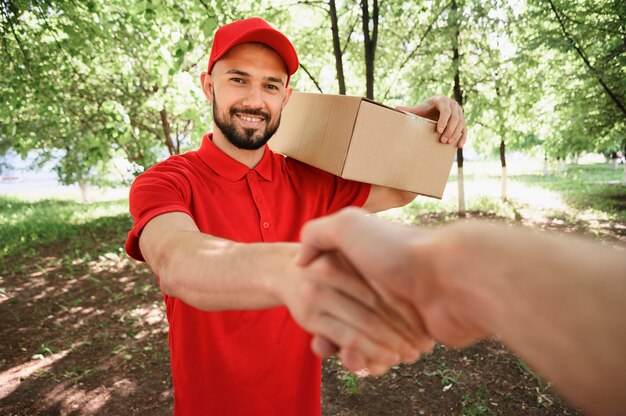 Retrato de repartidor estrechándole la mano con el cliente