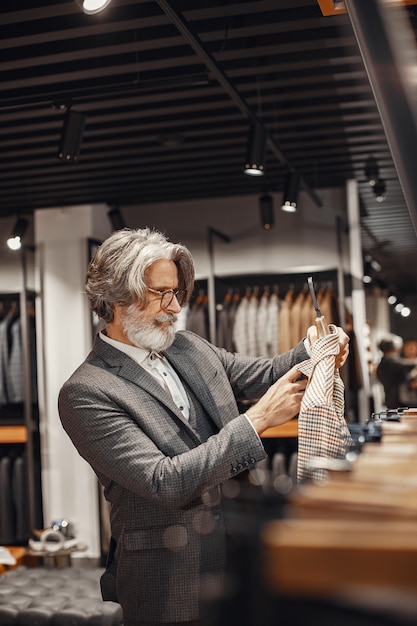 Foto gratuita retrato de un rico hombre maduro. senior visitando una boutique de moda. hombre compra un nuevo disfraz exclusivo.