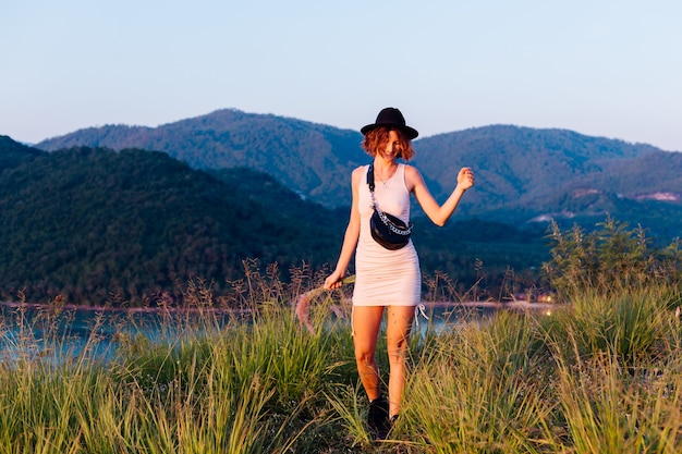 Retrato romántico de joven mujer caucásica en vestido de verano disfrutando de relajarse en el parque en la montaña con increíbles vistas al mar tropical Mujer en viajes de vacaciones alrededor de Tailandia Mujer feliz al atardecer