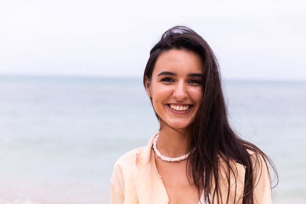 Retrato romántico de mujer en la playa en día ventoso, luz cálida del atardecer.